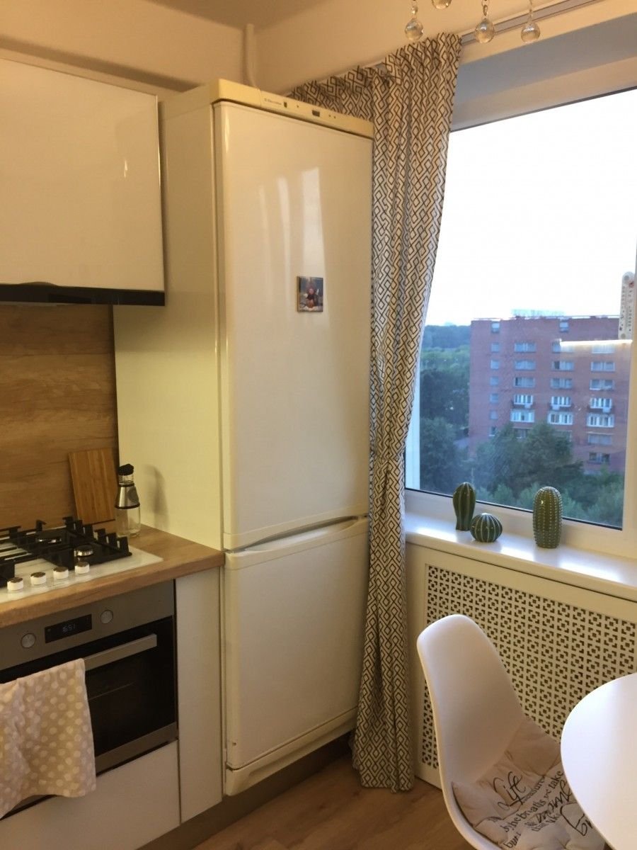 Холодильник возле окна на кухне