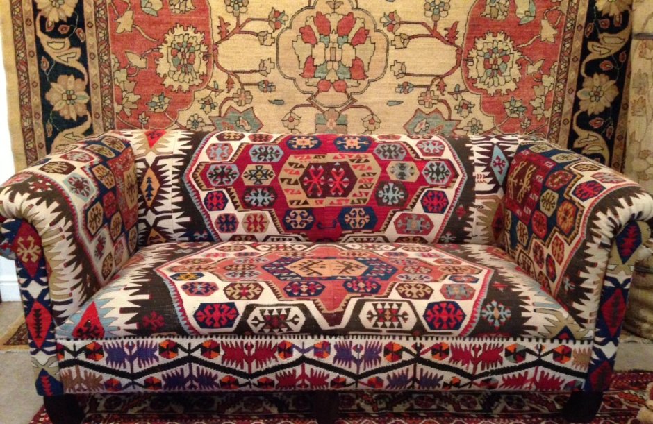 Диван с ковром на стене